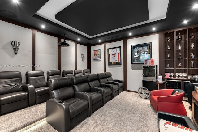 carpeted home theater room with a tray ceiling