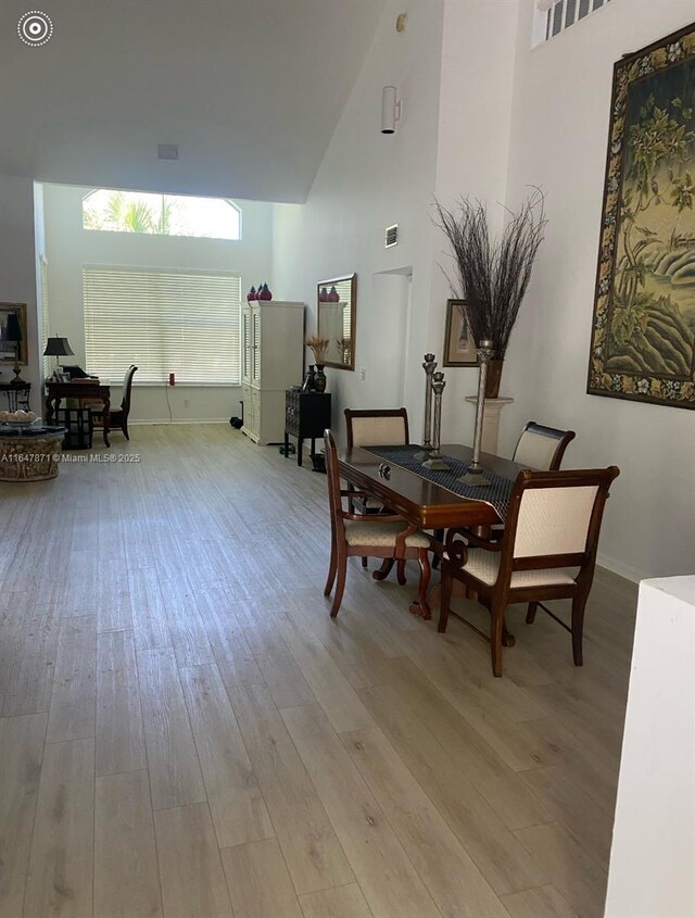 dining area with a high ceiling and light hardwood / wood-style flooring