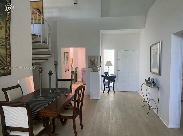 dining room featuring a towering ceiling and light wood-type flooring