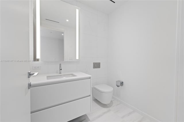 bathroom with vanity, toilet, and tile walls