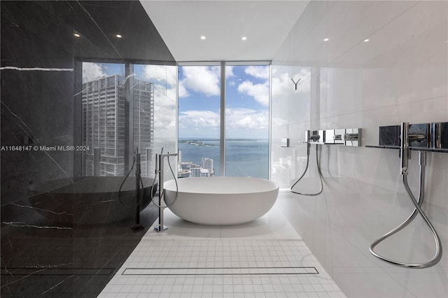 bathroom with a water view, plus walk in shower, tile patterned floors, a wall of windows, and tile walls