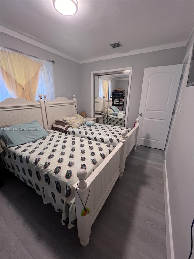 bedroom featuring dark hardwood / wood-style floors, crown molding, and a closet