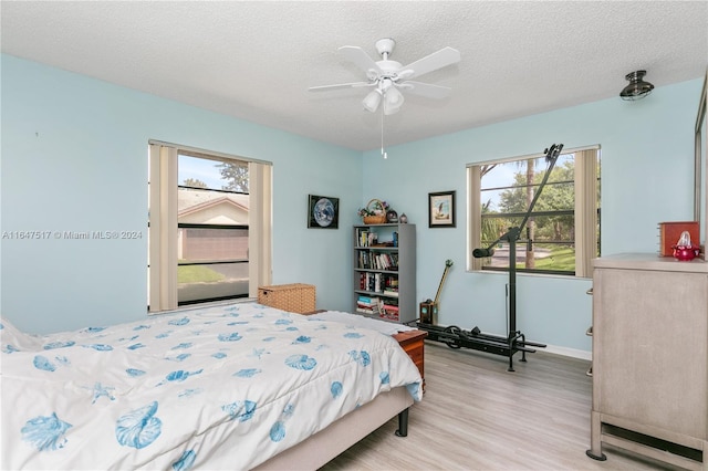 bedroom with ceiling fan, light hardwood / wood-style floors, and a textured ceiling