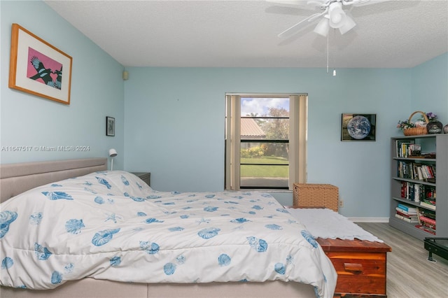 bedroom with a textured ceiling, light hardwood / wood-style flooring, and ceiling fan