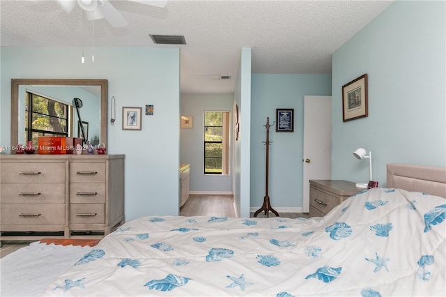 bedroom with ceiling fan, light wood-type flooring, and a textured ceiling