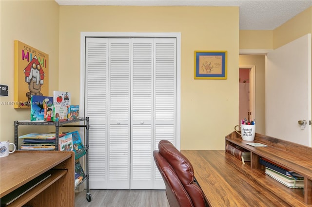 office with light hardwood / wood-style floors and a textured ceiling