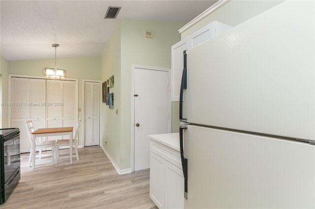 kitchen featuring decorative light fixtures, light wood-type flooring, white cabinets, vaulted ceiling, and white fridge