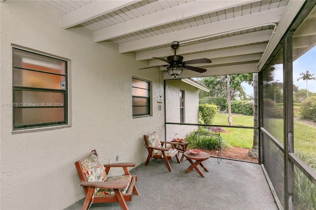 unfurnished sunroom featuring beam ceiling and ceiling fan