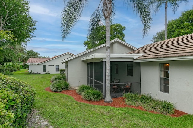 back of property featuring a sunroom and a lawn