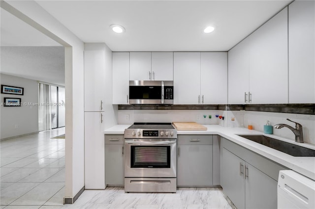 kitchen featuring appliances with stainless steel finishes, light tile patterned floors, gray cabinets, and sink