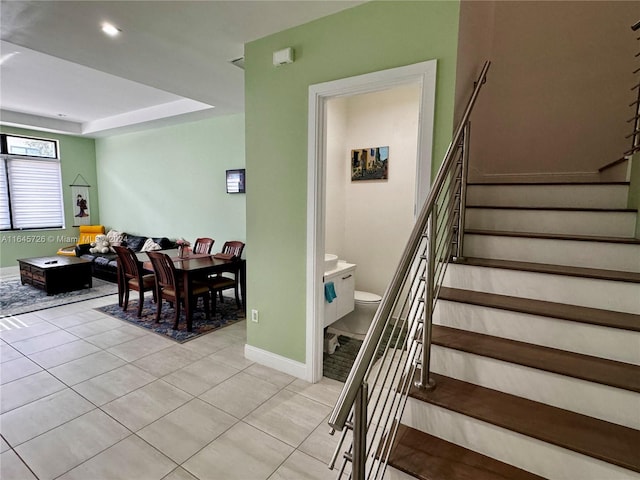 staircase featuring tile patterned flooring and a tray ceiling