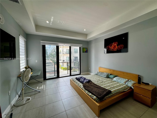 bedroom featuring access to outside, a tray ceiling, and light tile patterned floors