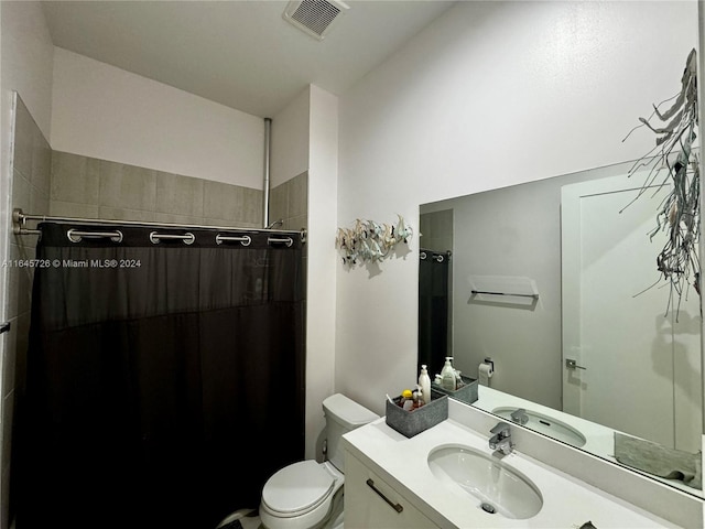 bathroom featuring toilet, vanity, and a shower with curtain