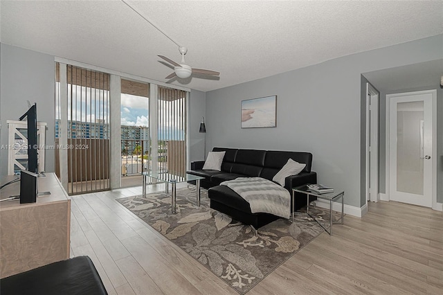 living room with ceiling fan, a textured ceiling, light hardwood / wood-style flooring, and expansive windows