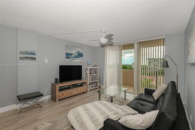 living room with light wood-type flooring, a textured ceiling, and ceiling fan