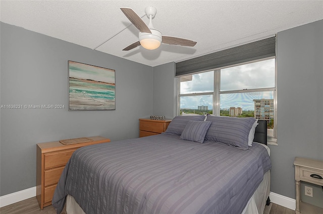 bedroom featuring ceiling fan, dark wood-type flooring, and a textured ceiling