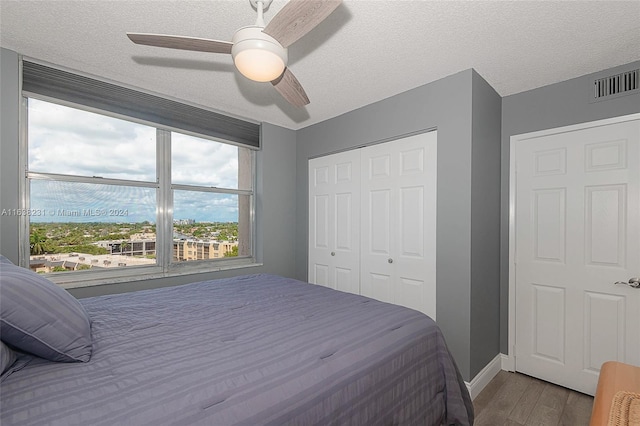 bedroom with ceiling fan, a closet, a textured ceiling, and wood-type flooring