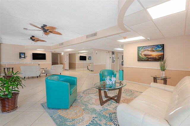 living room with ceiling fan, light tile patterned floors, and a paneled ceiling