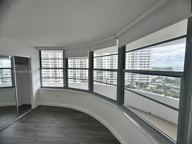 unfurnished bedroom with a closet, dark hardwood / wood-style flooring, and multiple windows