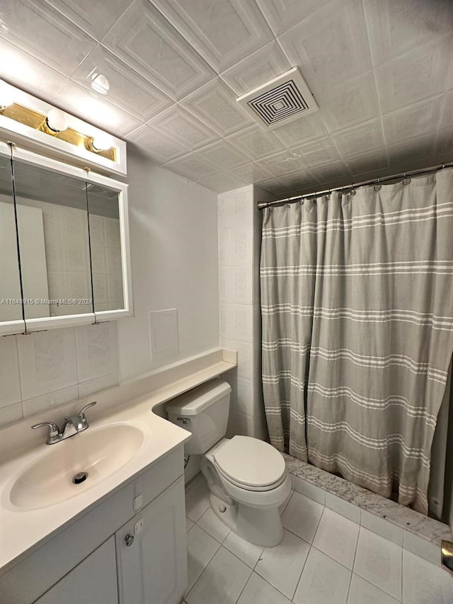 bathroom with toilet, tile patterned flooring, vanity, tile walls, and curtained shower