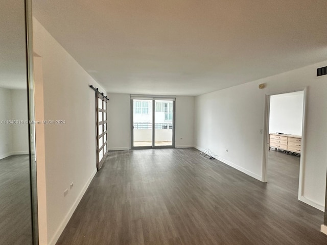 empty room featuring dark wood-type flooring and a barn door