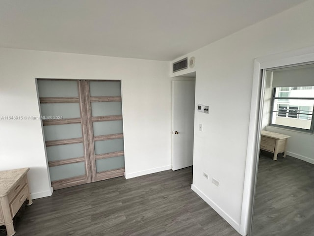 unfurnished bedroom featuring dark hardwood / wood-style floors and a closet