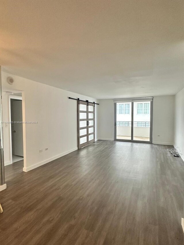 unfurnished room featuring dark hardwood / wood-style floors and a barn door