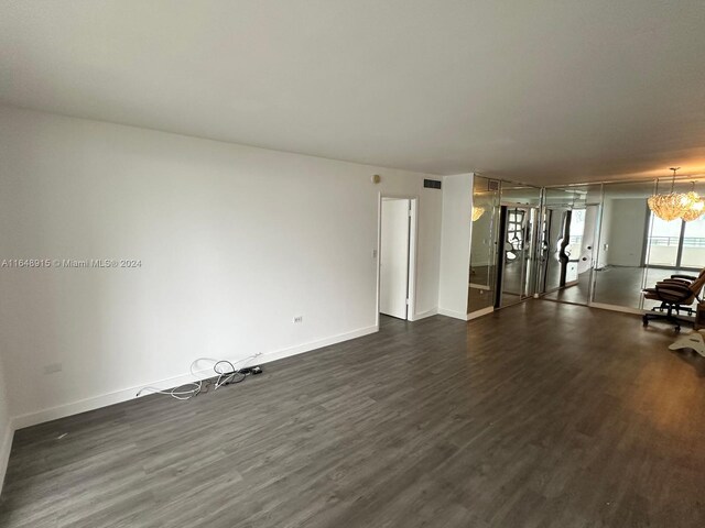 unfurnished living room featuring dark hardwood / wood-style floors and a chandelier