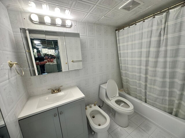 full bathroom featuring vanity, shower / bath combo with shower curtain, tile patterned floors, tile walls, and toilet