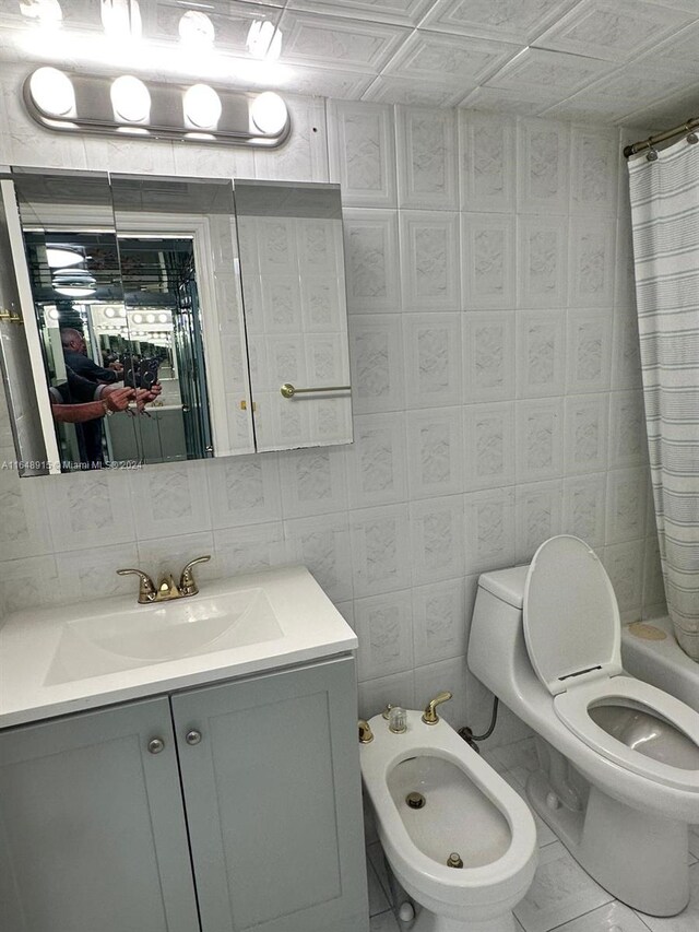 full bathroom featuring a bidet, tile patterned floors, vanity, tile walls, and toilet