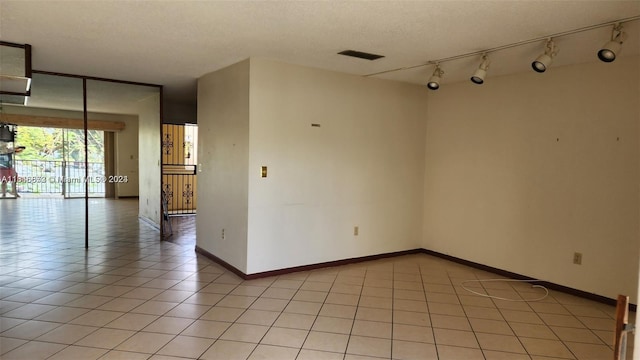 unfurnished room with light tile patterned floors, track lighting, and a textured ceiling