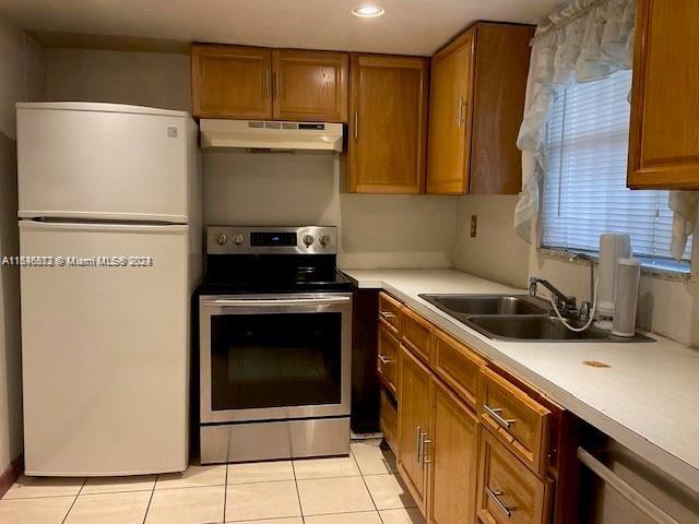 kitchen featuring light tile patterned flooring, sink, white fridge, and stainless steel electric range