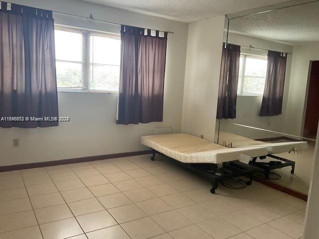 interior space featuring multiple windows, a textured ceiling, and light tile patterned flooring