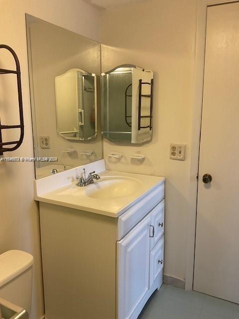 bathroom featuring tile patterned flooring, toilet, and vanity