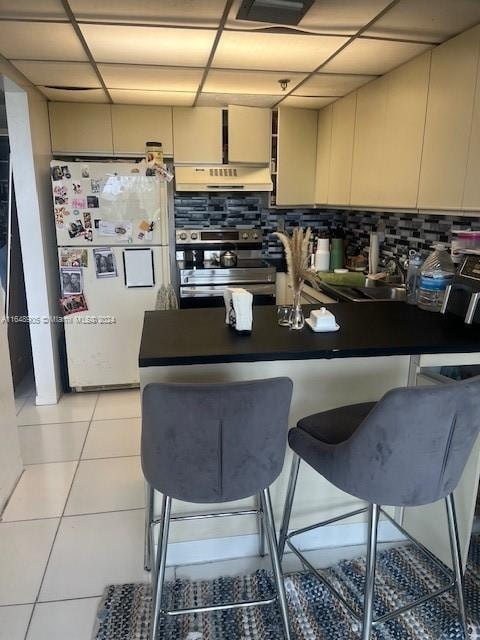 kitchen featuring a drop ceiling, decorative backsplash, and white fridge