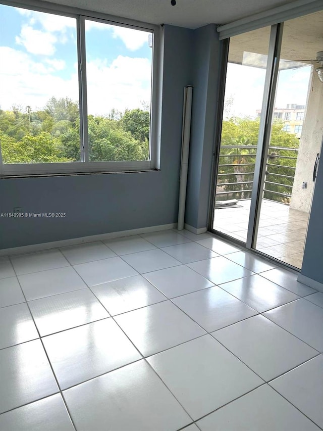 unfurnished room with light tile patterned floors and baseboards