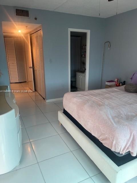 tiled bedroom featuring a closet and ensuite bathroom