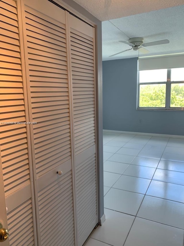corridor featuring tile patterned flooring, a textured ceiling, and baseboards