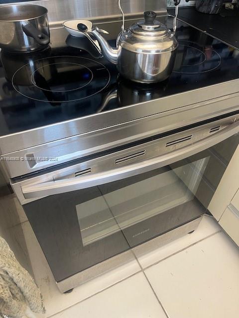 interior details with electric range and tile patterned floors