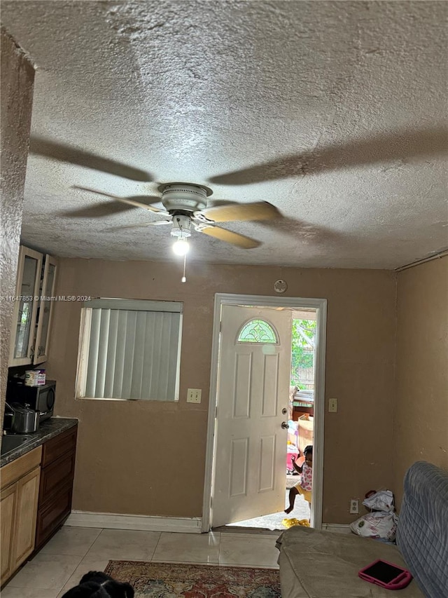 entrance foyer with a textured ceiling, ceiling fan, and light tile patterned floors