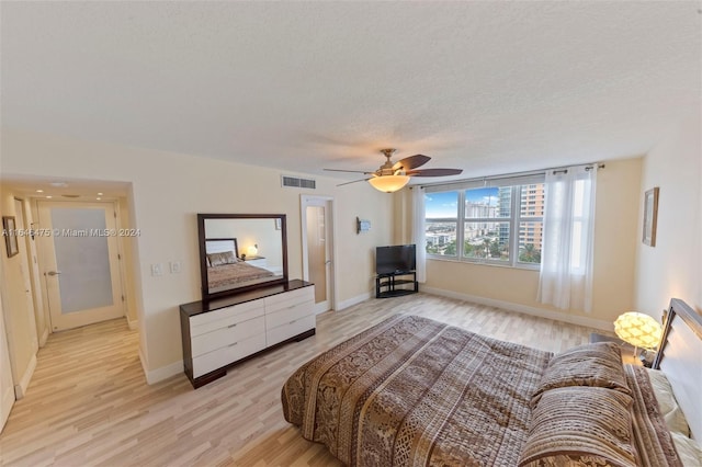 bedroom with ceiling fan, light hardwood / wood-style floors, and a textured ceiling