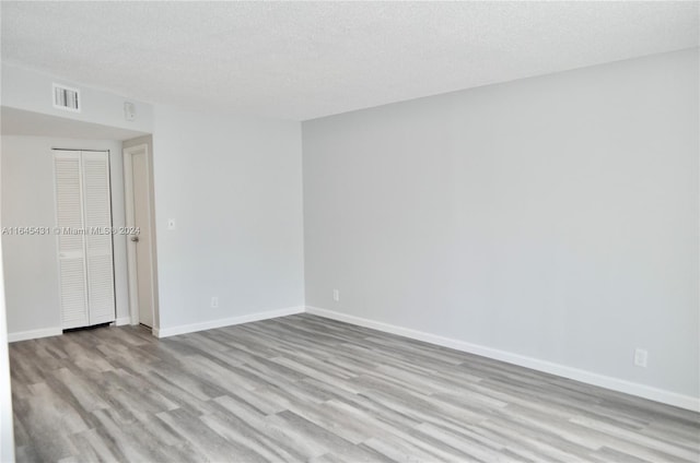 spare room featuring light wood-type flooring and a textured ceiling