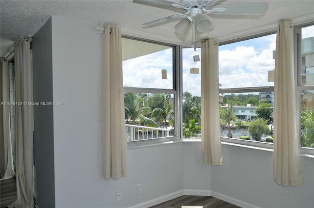 empty room with ceiling fan, a water view, and a wealth of natural light