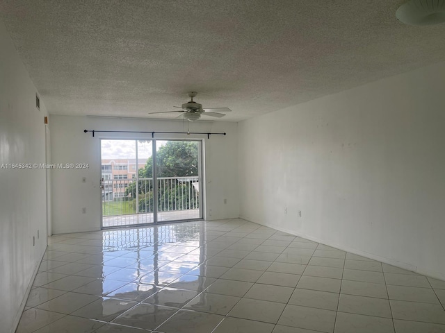 tiled spare room with a textured ceiling and ceiling fan