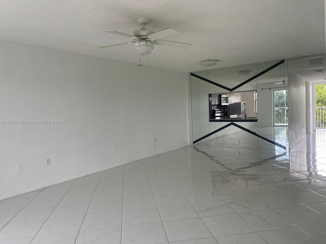 tiled spare room featuring ceiling fan and a textured ceiling