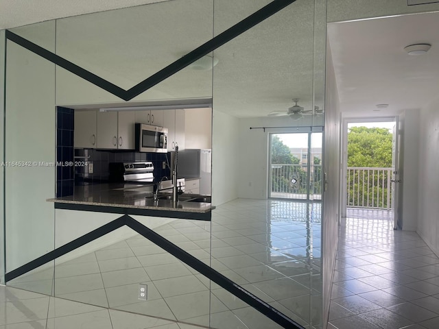 kitchen featuring stainless steel appliances, sink, light tile patterned flooring, ceiling fan, and decorative backsplash