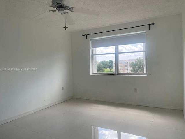 unfurnished room with a textured ceiling, light tile patterned floors, and ceiling fan