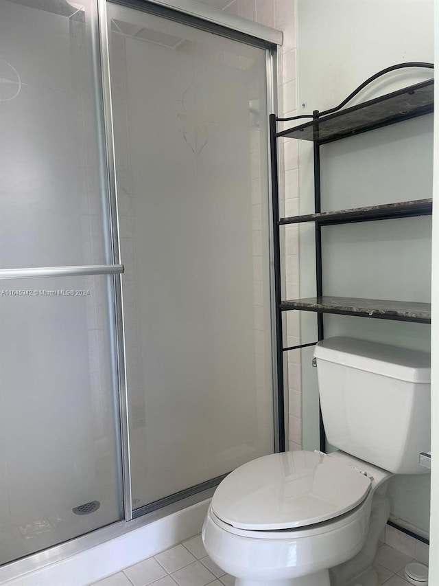 bathroom featuring toilet, an enclosed shower, and tile patterned floors