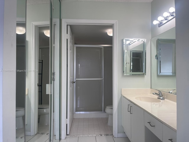 bathroom featuring a shower with door, vanity, toilet, and tile patterned flooring