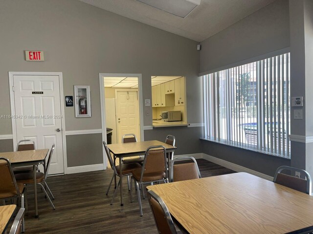 dining area with high vaulted ceiling and dark hardwood / wood-style floors